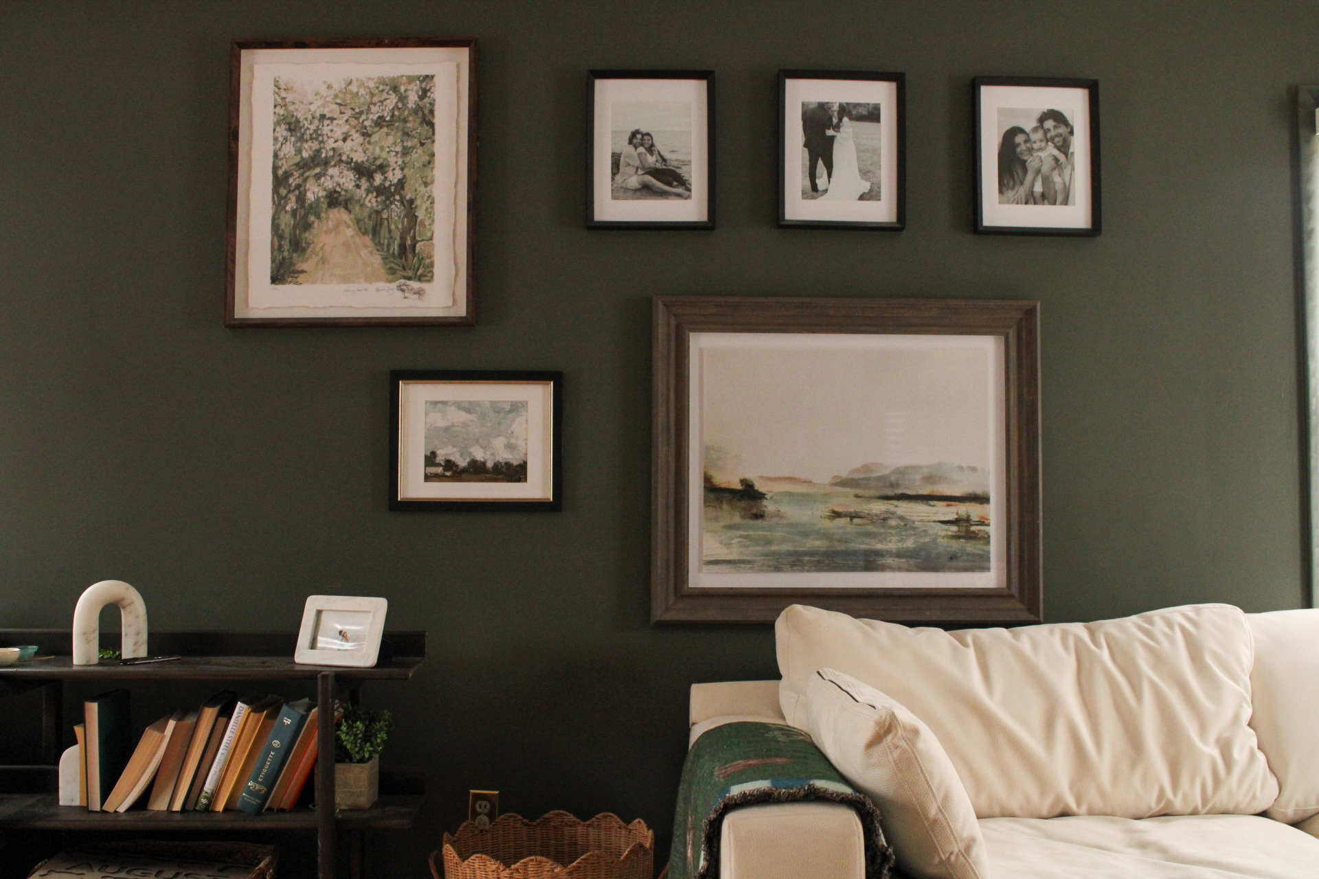 Gallery wall with framed art and photographs above a cream sofa