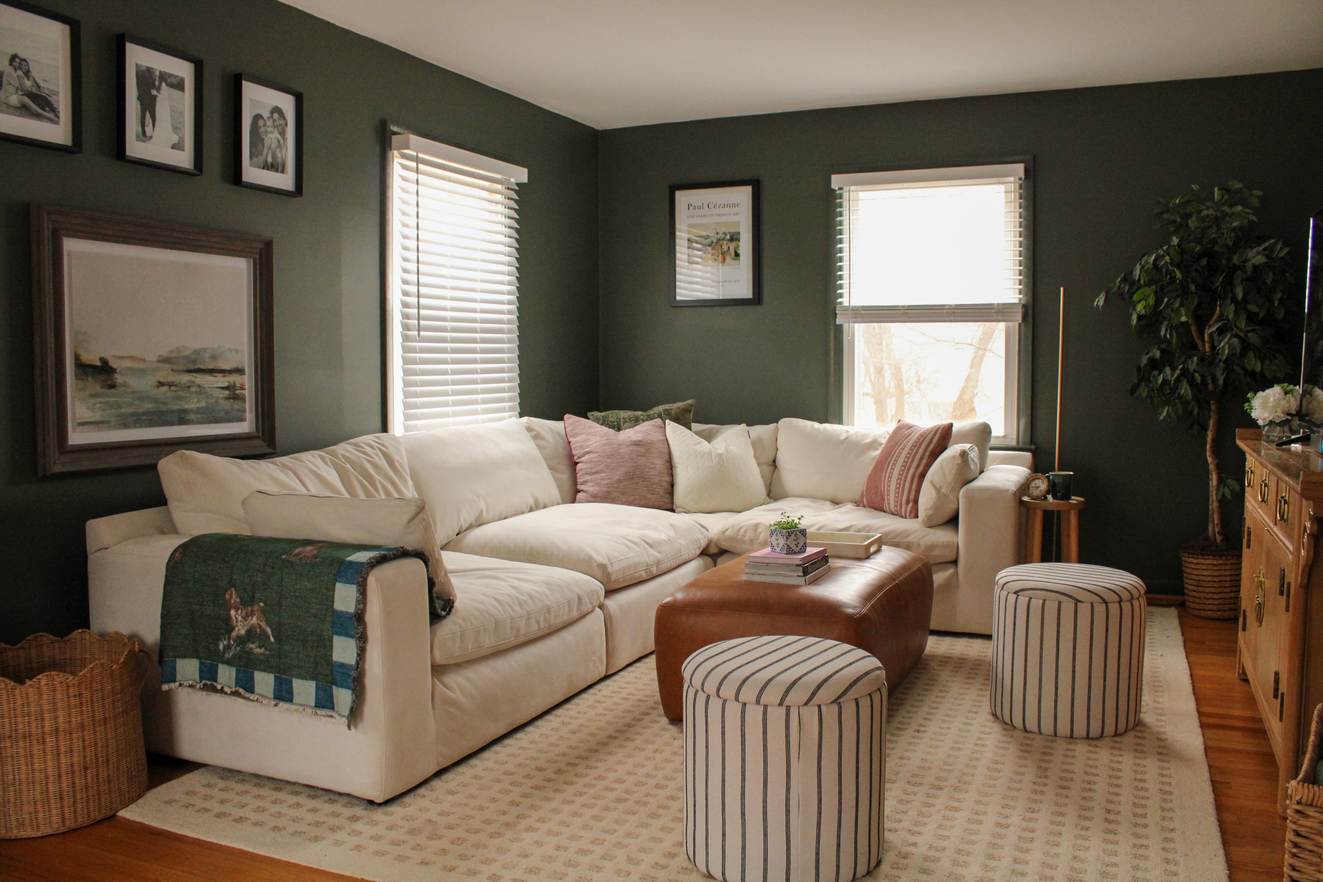 Living room with green walls, cream sectional, and natural light